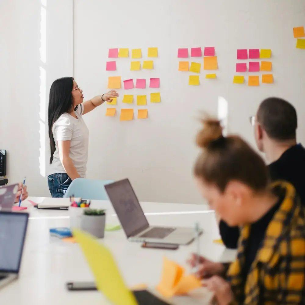 Planning wall with sticky notes and a team at work