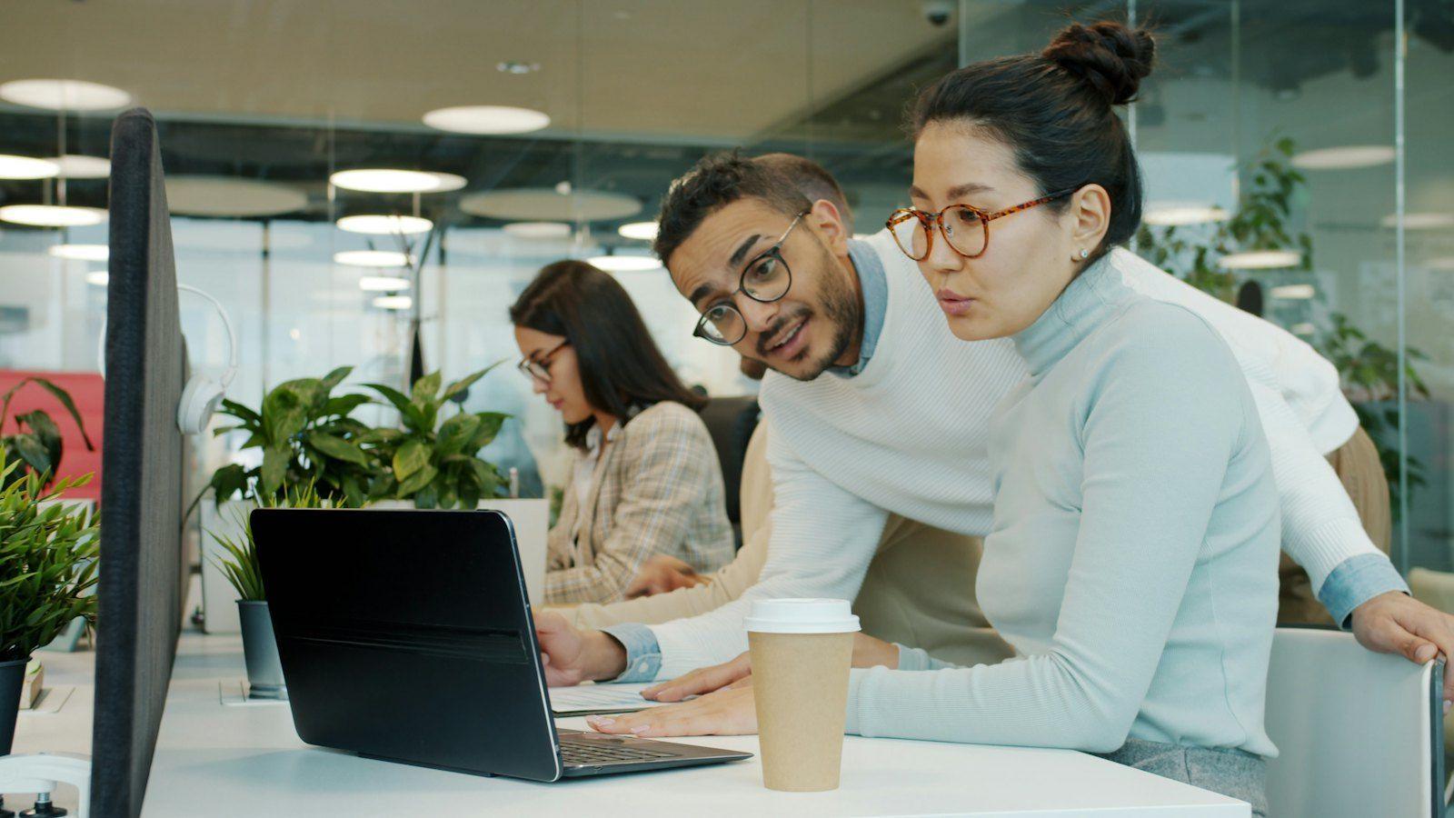Colleagues gathered around a laptop in a modern office